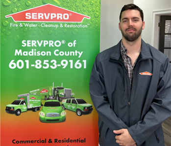 SERVPRO employee standing in front of SERVPRO pop-up banner
